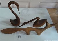 Three wood carvings placed on white surface, showing two bird sculptures and one fox.