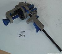 Photo of Wilton multi grip clamp system showing ergonomic trigger handle, clamp jaw with rotating base and locking mechanism, rubber pads on jaw surfaces.