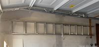 Aluminum extension ladder mounted horizontally in garage, showing the rungs and partial length