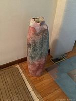 Front view of glazed clay vase showing pastel pink, blue, and gray tones with irregular shape and rim.