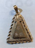 Front angled view showing the layered pyramid shape with three clear stones set in a star pattern and twisted rope border.