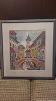 Framed colorful serigraph print showing Venetian bridge and buildings, full view.