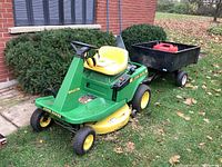 Front view of John Deere SRX 74 riding mower with attached utility trailer and gas can