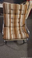 Front view showing the tufted cushion with brown, beige, and white striped pattern and chrome tubular metal frame