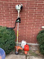 Full view of trimmer upright with harness and accessories at base