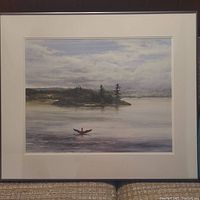 Full view of the framed and matted watercolor painting showing a loon on a lake with an island and cloudy sky.