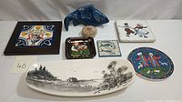 Overview of the full collection showing all items including framed tile trivet, small trinket dishes, ceramic fish sculpture, and centerpiece dish with landscape design