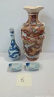 Front view of two porcelain vases and two small dishes on flat surface, showing size comparison and overall design.