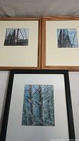 Three framed mixed-media paintings by Donald Gotz showing a fishing net theme and a landscape with trees.