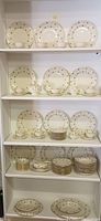 Shelves of Lamberton China dinnerware including plates, bowls, cups, saucers, and serving pieces all decorated in floral and gold trim pattern.
