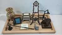Various metal decorative and collectible items on wooden tray including enamel vase, picture frame, candlestick with frog figure, easel stand, bird bookends, and music box.