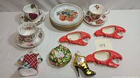 View of salad plates, teacups with saucers and Christmas-themed ornaments on a white background.