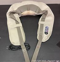 Top view of cervical massage shawl with beige and gray soft material, control panel with buttons and display, power cord attached.