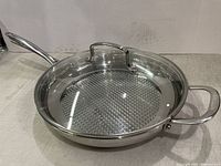 Side angle of stainless steel skillet showing embossed cooking surface and side handles.
