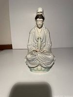 Front view showing seated Guan Yin goddess holding a vase, detailing facial features, robes, and lotus pedestal base.