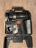 Tacklife cordless drill kit inside carrying case with charger, battery, accessory kit, and drill bits.