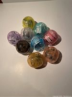 Nine colorful transparent plastic Gacha balls used for packaging the mini wands, arranged in a cluster.