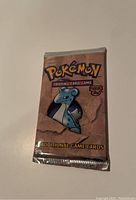 Front of sealed Pokémon Fossil booster pack showing Lapras artwork on brown packaging with “Additional Game Cards” text