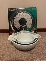 Set of three nested blue and white Pyrex dishes in front of boxed Satin Frost wreath platter.