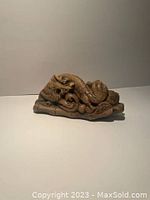 Side view of carved stone Chinese dragon showing detailed scales and curled body.