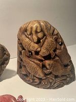 Close-up of a carved stone figurine featuring three koi fish and detailed aquatic carvings