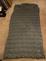 Full view of the king size grey weighted blanket with quilted stitching laid out on the floor.