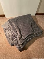 Folded grey quilted winter cover for weighted blanket, soft plush material shown on carpet.