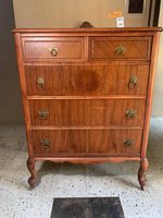 Full front view of antique wooden dresser showing drawers, handles, and legs with casters.