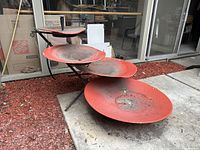 Front-left view showing four stacked red dishes and black metal frame