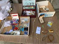 Photo showing several bead bracelets, metal rosary chains, necklaces with crosses, and a jewelry box.