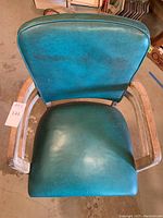 Top view of chair showing teal green leatherette backrest and top of unfinished wooden arms