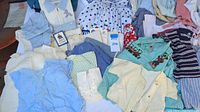 Overview of various infant clothing including dresses, sweaters, hats, and accessories laid out on a white surface