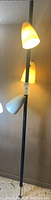 Full view of lamp showing black tension rod and three conical shades in yellow and white
