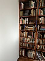 Full view of eight wooden shelves filled with a variety of books including classics, novels, and biographies.