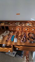 Full view of the costume jewelry collection laid out on a wooden surface showing necklaces, bracelets, and pins.