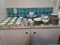 Overall view of plates, cups, bowls and serving pieces laid out on countertop