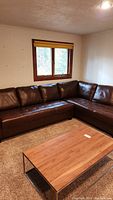 Full view of the sectional sofa set up in a room with carpet and adjacent wooden coffee table
