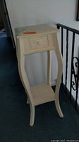Tall cream painted wooden side table with curved legs, single drawer with round knob, and lower shelf shown from front angle.
