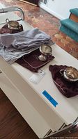 Lot displayed on white table including sterling cups and pourer on cloth bags, showing tarnish and condition.