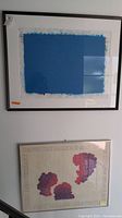 Overall view of the two framed Judy Targan art pieces hanging on a white wall, showing size and framing.