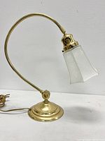 Side view of brass lamp with curved whiplash neck and frosted etched glass fluted shade.
