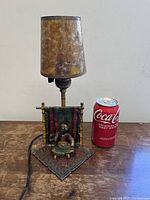 Front view of lamp with mica shade and bronze base alongside soda can for scale