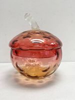 Front view of amberina glass strawberry shaped lidded bowl with coin dot pattern and clear stem handle
