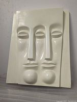 Front view of Mid-Century Modern fiberglass wall sculpture, showing two stylized long faces with smooth finish and off-white color.