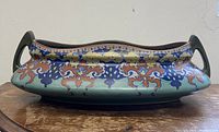 Front view of oval bowl showing polychrome Art Nouveau decoration and dual handles