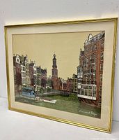 Full view of framed lithograph showing Amsterdam cityscape and signature in lower right corner.