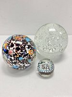 All three paperweights placed together showing clear bubble design and colorful millefiori patterns.