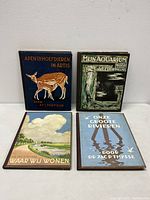Set of four hardcover vintage cigarette sticker albums with nature-themed illustrated covers visible on top, showing deer, aquatic creatures, countryside, and birds with blue and green color schemes.