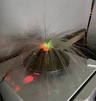 Lamp powered on displaying colorful light dots at strand ends, showing working fiber optic feature