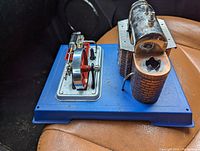 Overall view of the Wilesco steam engine toy showing the boiler, flywheel, and burner unit without chimney on the blue base.